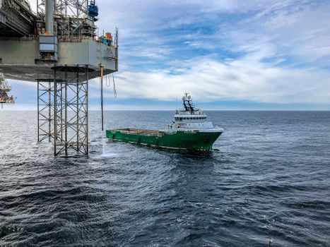 Supply vessel approaching offshore oil platform in Danish waters, showcasing maritime industry.